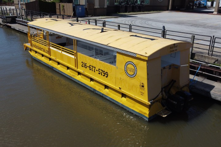 Yellow water taxi docked by a riverside walkway on a sunny day.