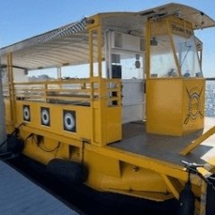 A yellow boat docked at a pier on a sunny day with a blue sky.