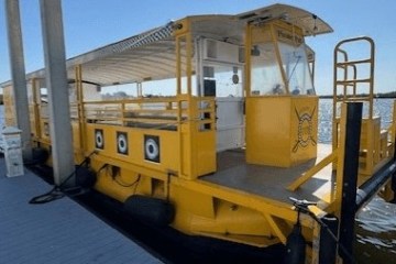 A yellow boat docked at a pier on a sunny day with a blue sky.
