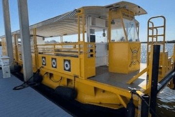 Yellow floating tiki bar moored at a dock on sunny day.
