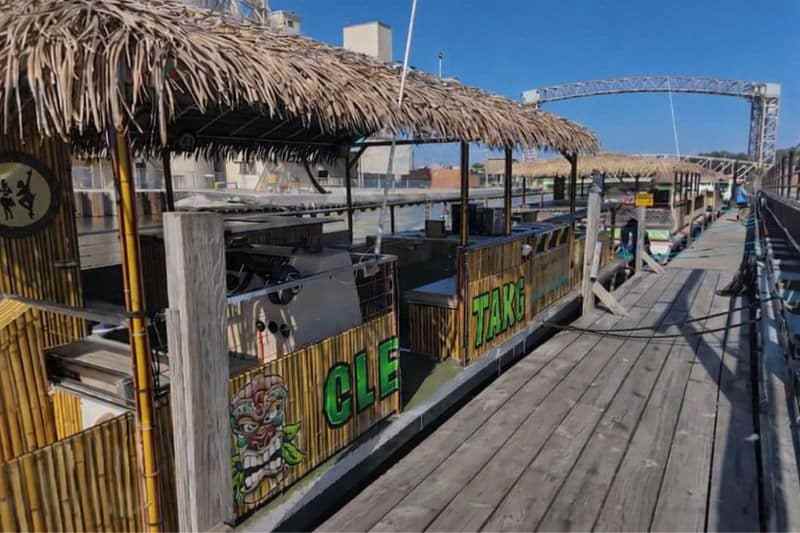 Tiki-style boats docked at a harbor with a bridge in the background.